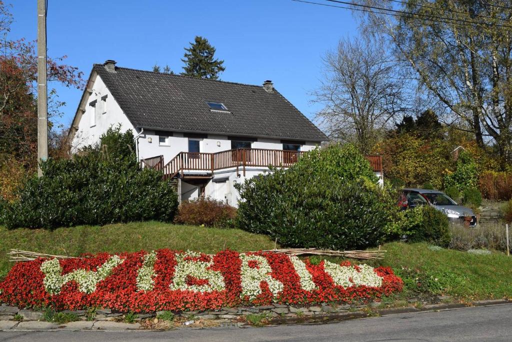 a house with a sign in front of a flower garden at La Villa Blanche in Houffalize