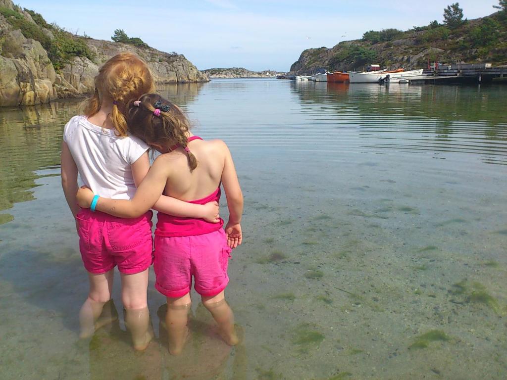 dos chicas de pie en el agua en la playa en Skottevik Feriesenter, en Skottevik