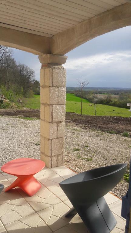 a patio with a table and a bench and a view of a field at Taillefer in Saint Paul de Loubressac