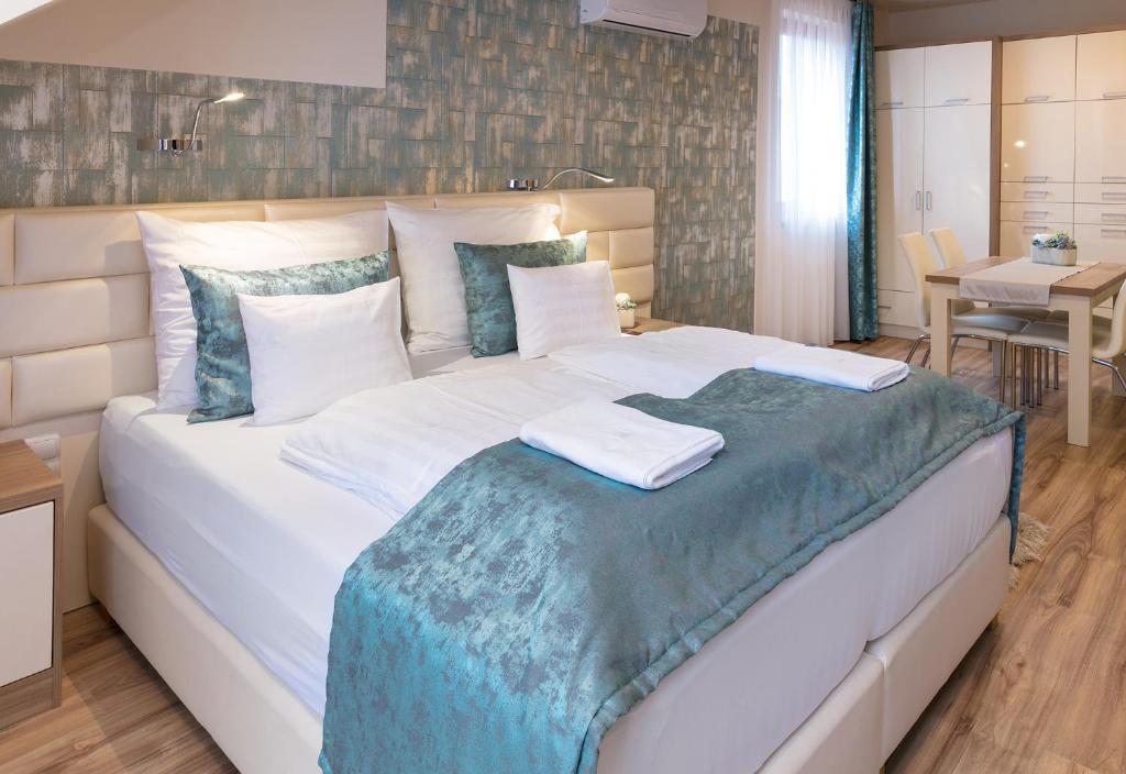 - une chambre avec un grand lit blanc et une couverture bleue dans l'établissement Főtér Rezidencia 3, à Győr