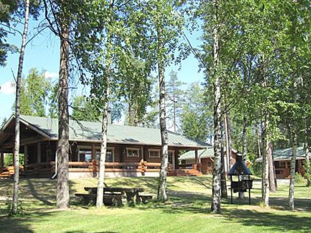 una baita di tronchi con un gruppo di alberi di fronte ad essa di Holiday Home Kivitasku by Interhome a Kallionkieli