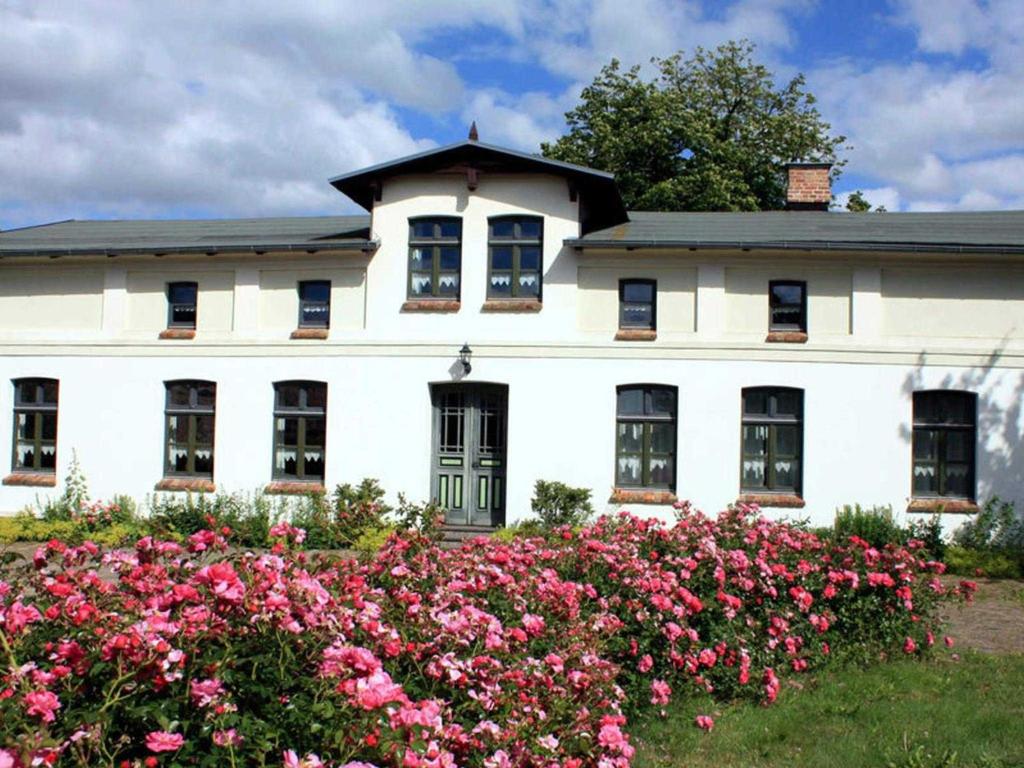 una casa blanca con flores rosas delante en Ferienwohnungen im Bauernhaus _ Ob, en Papendorf