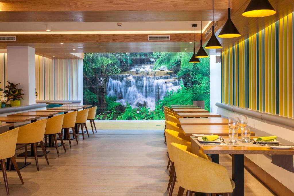 a restaurant with a waterfall mural on the wall at Vanilla Garden Boutique Hotel - Adults Only in Playa de las Americas