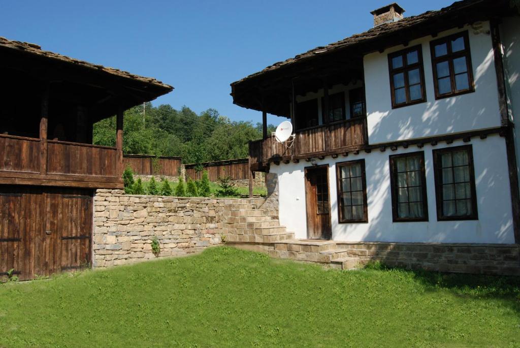 a white house with a wooden door and a yard at Къща Балканец in Balkanets