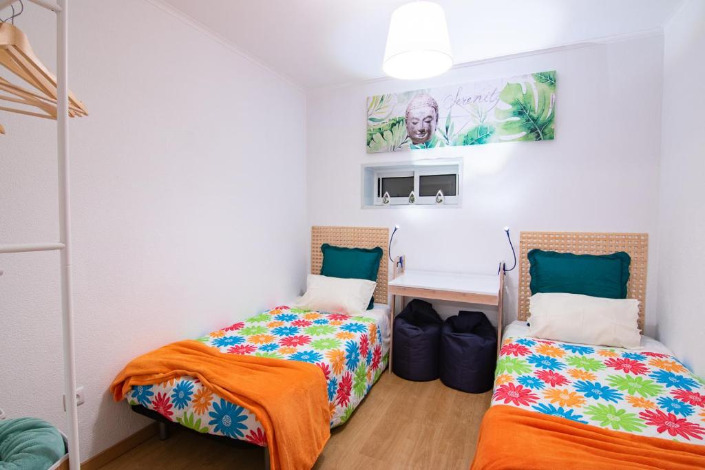 a bedroom with two beds and a desk at Herama Garden Guesthouse in Vila Nova de Gaia