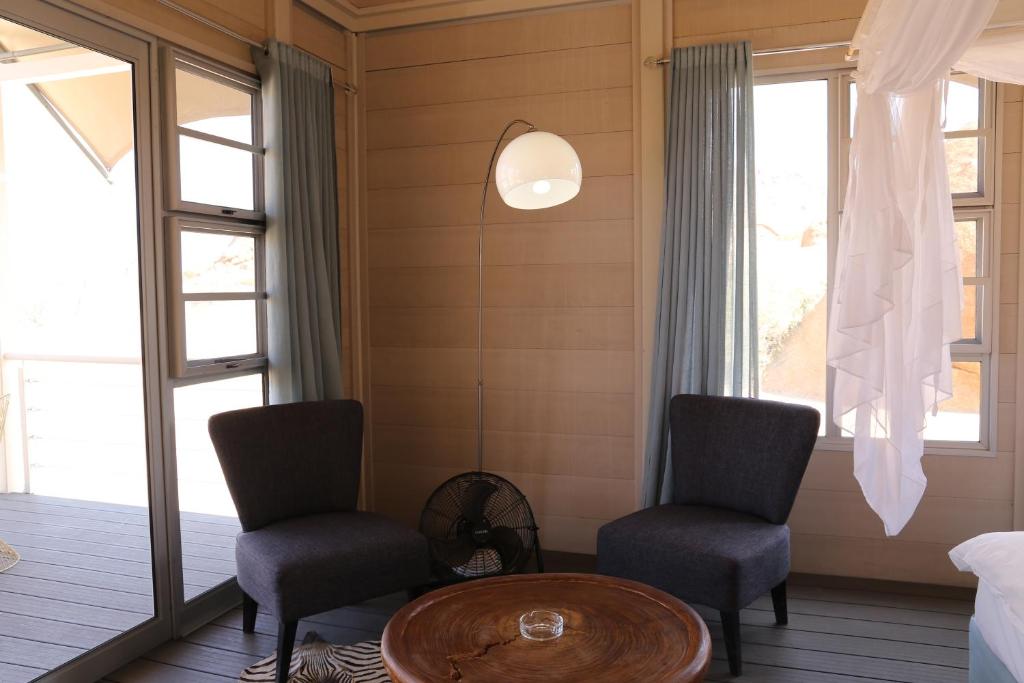 two chairs and a table in a room with windows at Spitzkoppen Lodge in Usakos