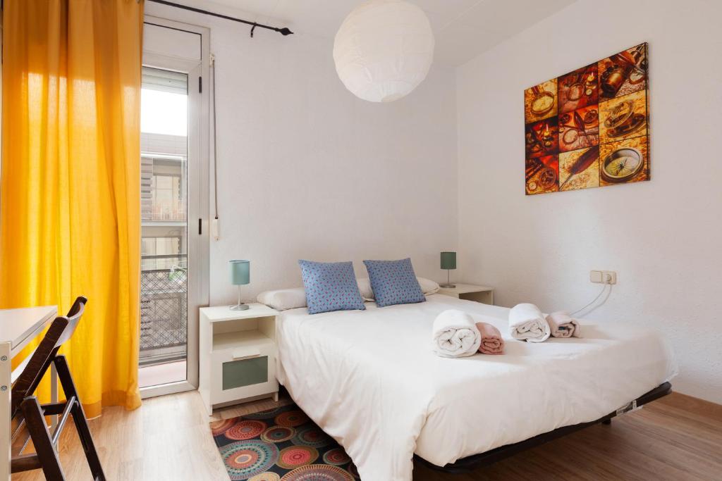 Un dormitorio con una cama blanca con almohadas azules y una ventana en Barnapartments Monumental en Barcelona