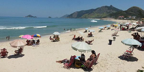 un grupo de personas sentadas en una playa con sombrillas en Casa Del Mar, en Río de Janeiro