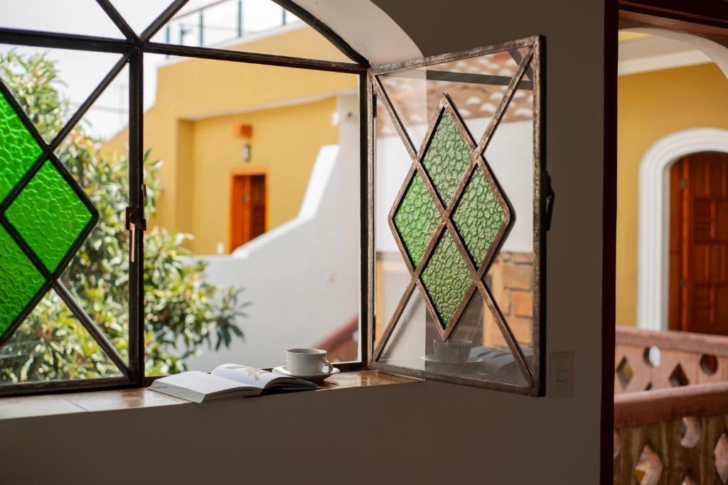 una ventana de cristal con un libro y una taza sobre una mesa en Casa Cafeólogo en San Cristóbal de Las Casas