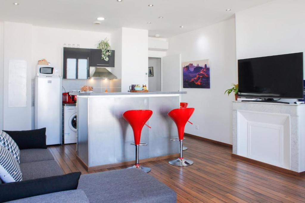 a living room with red chairs and a kitchen at Les quais du Port in Marseille