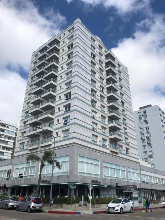 un edificio alto con coches estacionados frente a él en Punta del Este Lux Tower, en Punta del Este