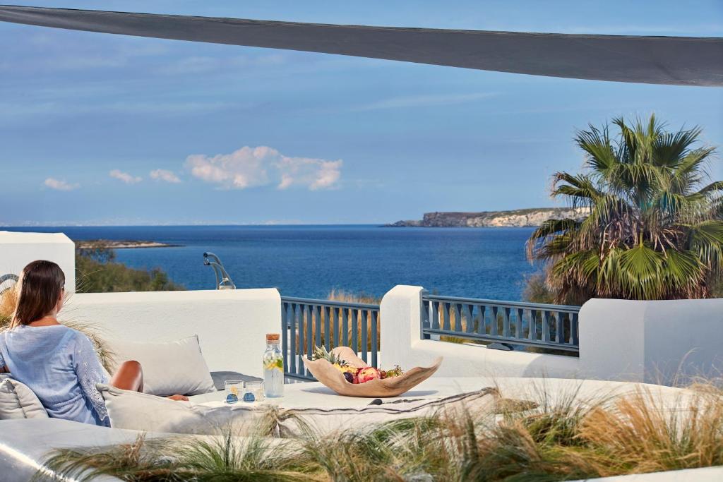 a woman sitting on a couch looking out at the ocean at Parian Boutique Hotel in Naousa