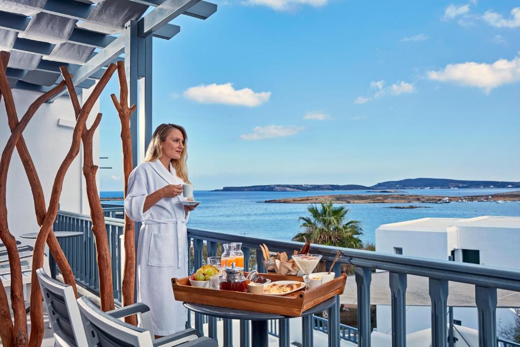 una donna in piedi su un balcone con un vassoio di cibo di Parian Boutique Hotel a Naoussa