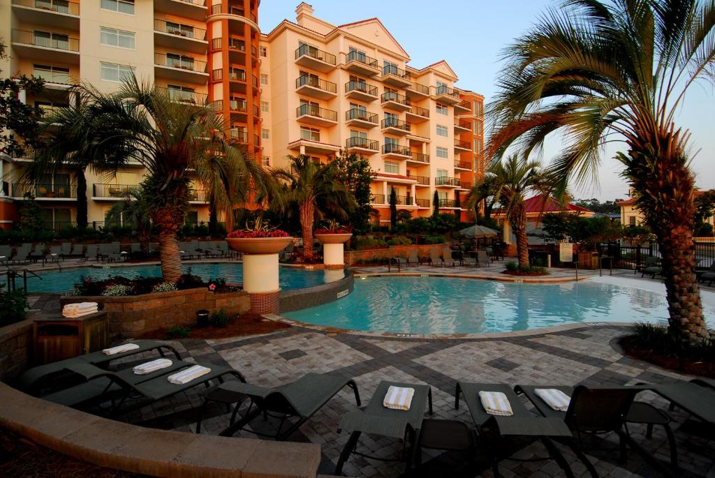 a resort pool with tables and chairs and palm trees at Marina Inn at Grande Dunes in Myrtle Beach