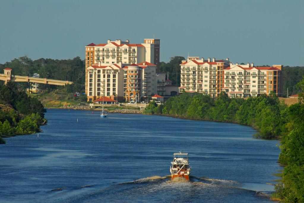 a boat traveling down a river with tall buildings at Marina Inn at Grande Dunes in Myrtle Beach