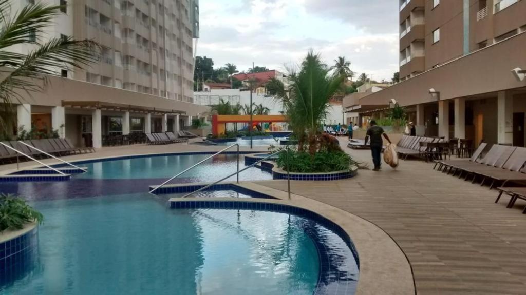 a woman walking by a swimming pool in a hotel at Apartamento no Olimpia Park Resort in Olímpia