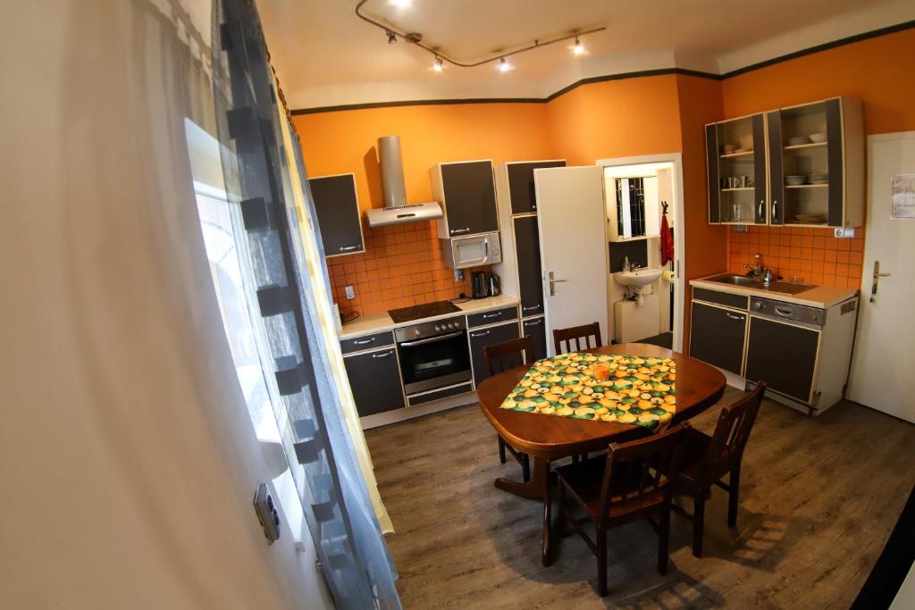 a kitchen with a wooden table with chairs and a kitchen with orange walls at Ljubljana apartment in Ljubljana