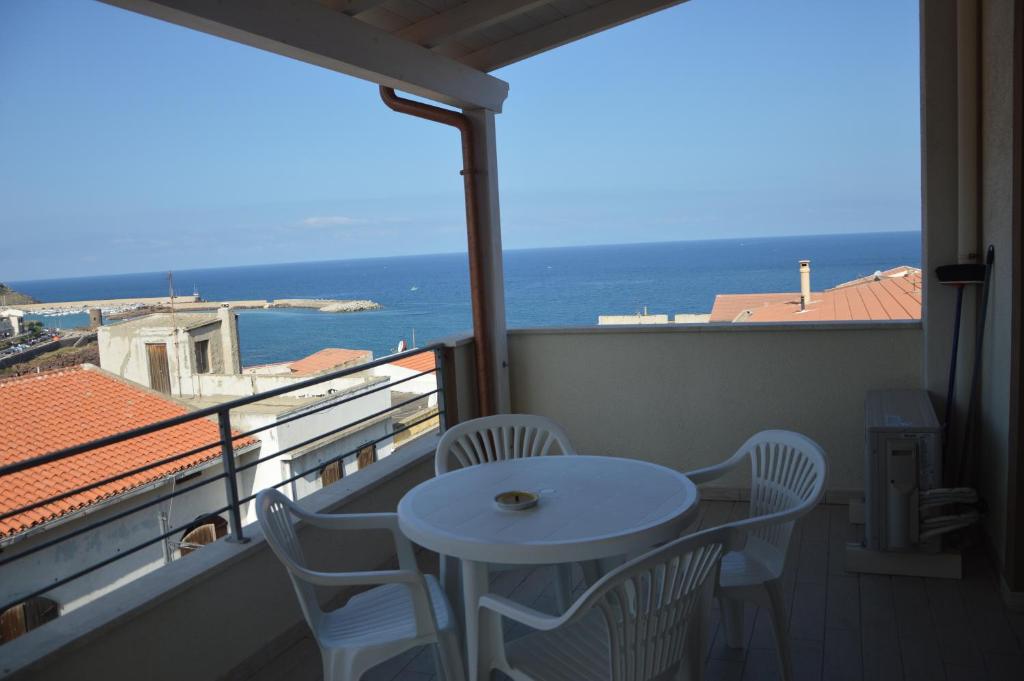 een witte tafel en stoelen op een balkon met uitzicht op de oceaan bij Appartamento 5 - Via Carlo Alberto n 26 - Immobileuro srl in Castelsardo