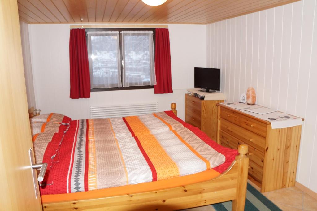 una camera da letto con un letto e una scrivania con una televisione di Haya a Naters