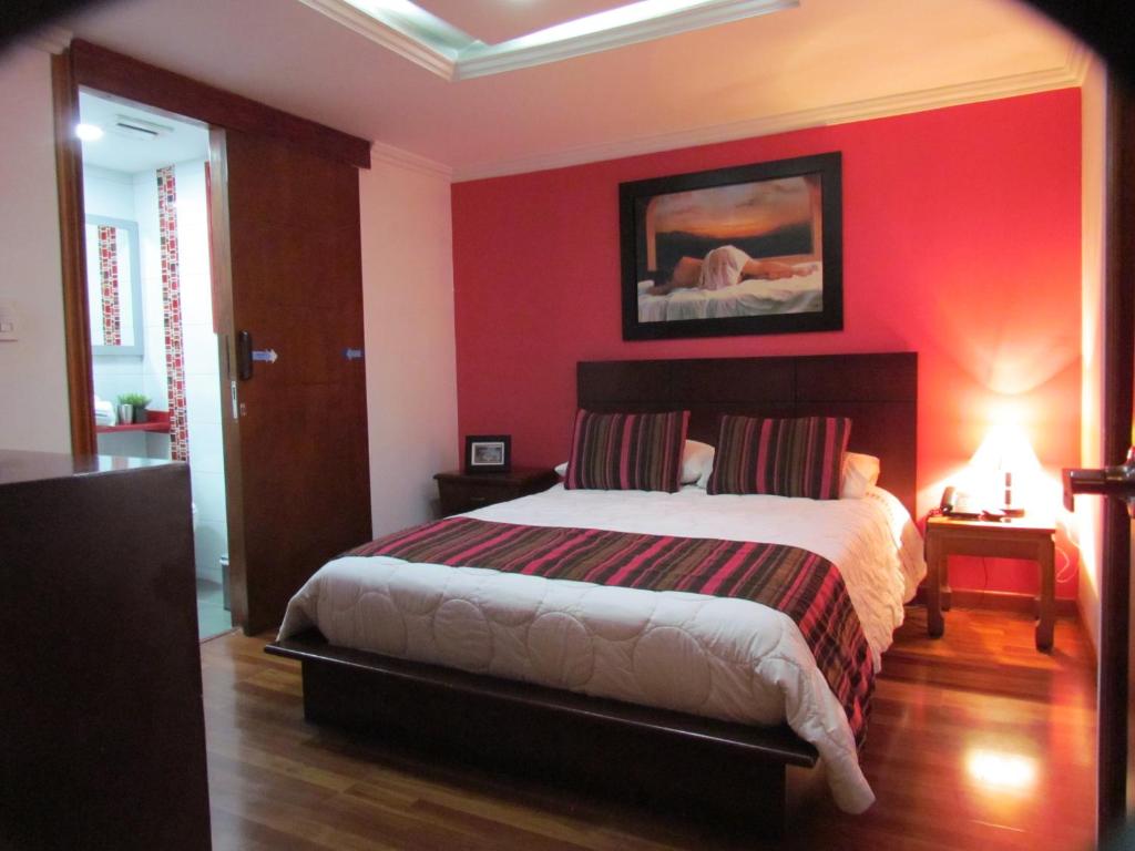 ein Schlafzimmer mit einem Bett mit einer roten Wand in der Unterkunft Hotel Apartasuite Normandia in Bogotá