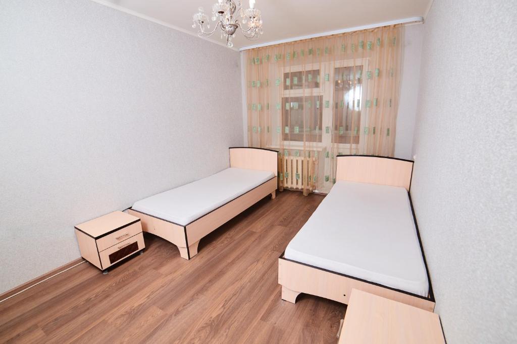 a room with two beds and a chandelier at Modus Apartment in Tobolsk