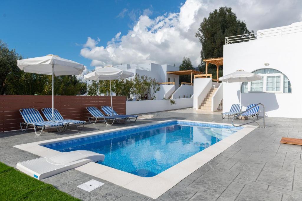 einen Pool mit Stühlen und Sonnenschirmen neben einem Haus in der Unterkunft Milos Villas Complex in Pefki Rhodes
