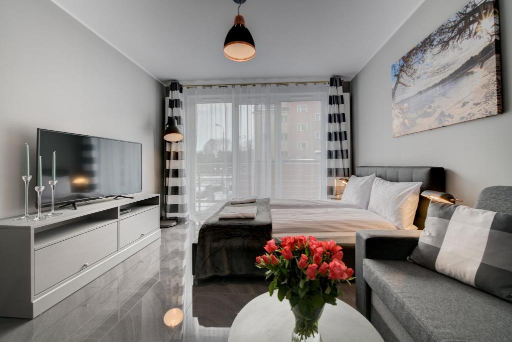 salon z łóżkiem i wazą kwiatów na stole w obiekcie Live & Travel Old Town Apartments w Gdańsku