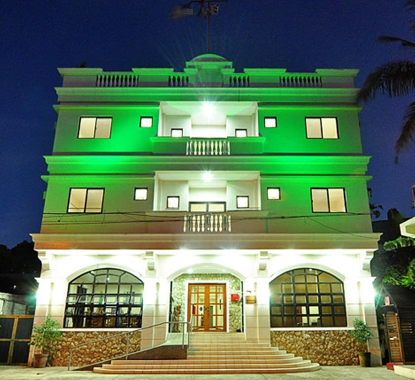 El Haciendero Private Hotel في إيلويلو سيتي: مبنى به إضاءة خضراء في الليل