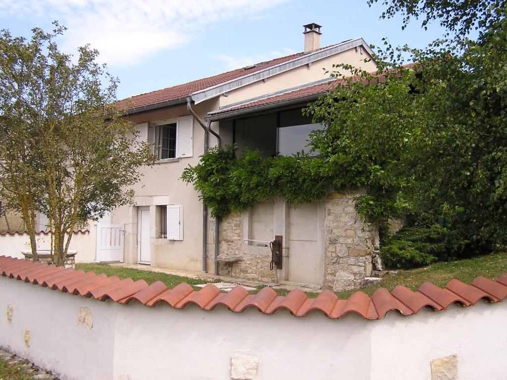 Gite de l'Ancheronne 12 couchages spa في Lavans-sur-Valouse: بيت ابيض بجدار واشجار