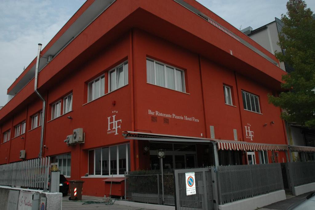 un bâtiment rouge avec une clôture devant lui dans l'établissement Hotel Fiera, à Bolzano