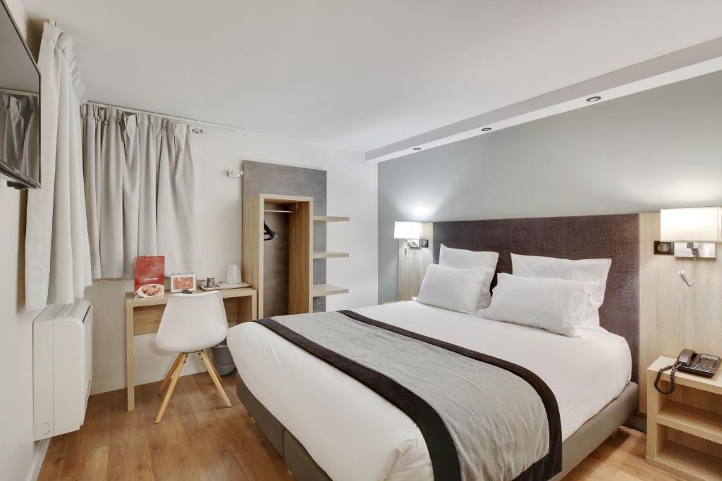 Schlafzimmer mit einem großen weißen Bett und einem Schreibtisch in der Unterkunft Hôtel l'Amandier in Nanterre