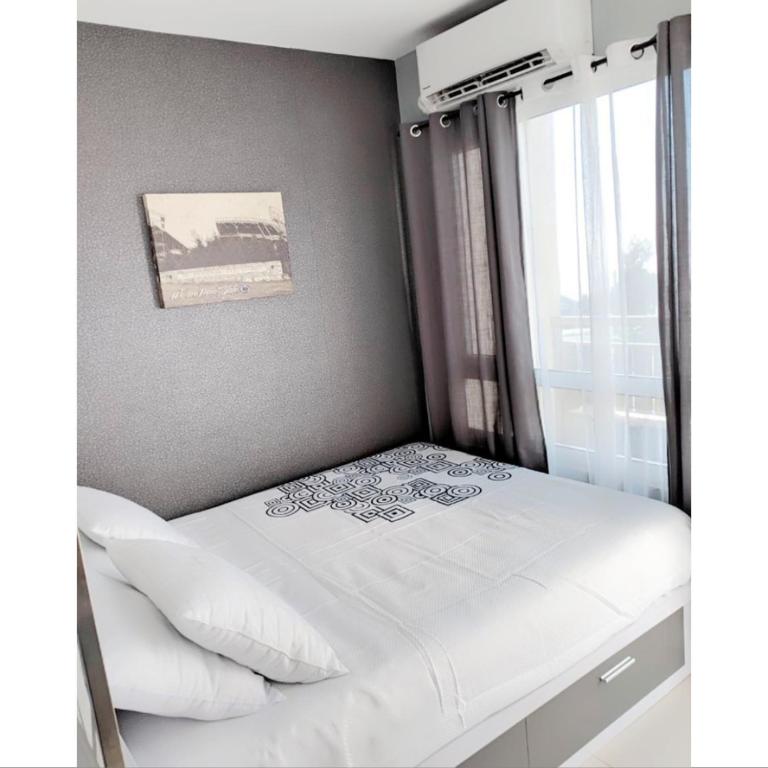 - une petite chambre avec un lit blanc et une fenêtre dans l'établissement The Penn Room Tagaytay at Cool Suites, à Tagaytay