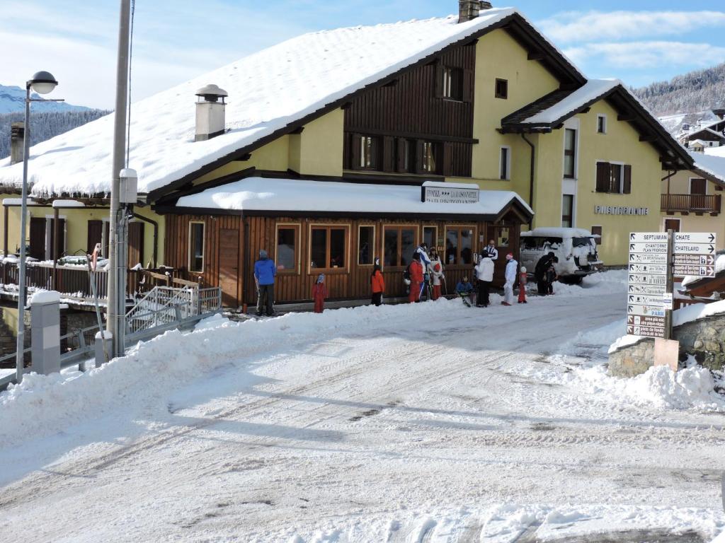 托爾諾的住宿－麥森訥特酒店，一群人站在一座建筑物外的雪中