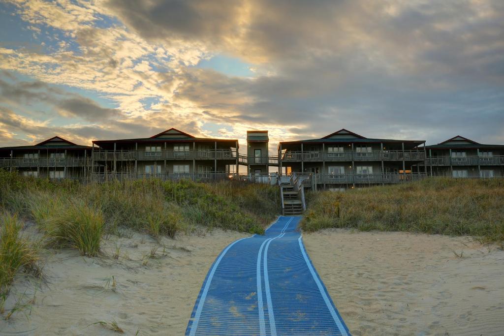 um resort na praia com uma passagem azul na areia em Outer Banks Beach Club em Kill Devil Hills