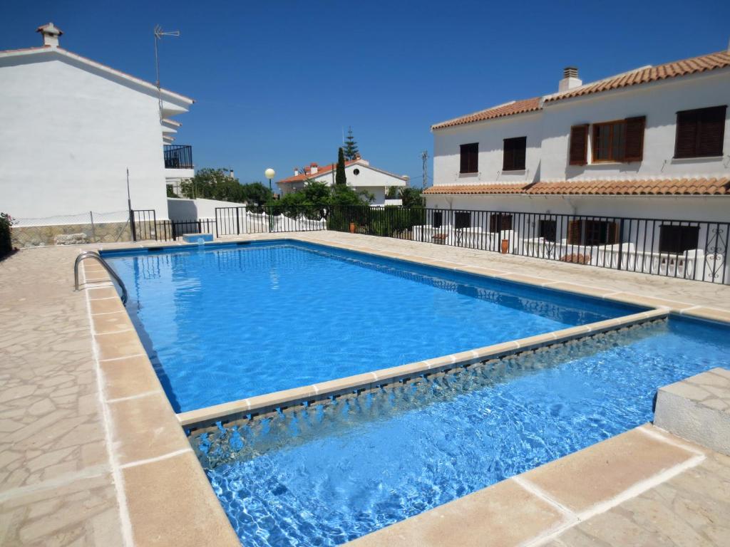 a swimming pool with blue water in front of a building at Peñíscola: apartamento con piscina in Peniscola