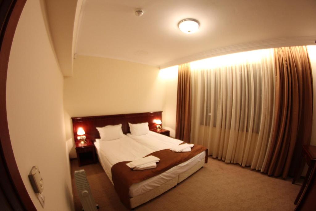 a hotel room with a large bed and a window at Downtown Bansko Resort in Bansko