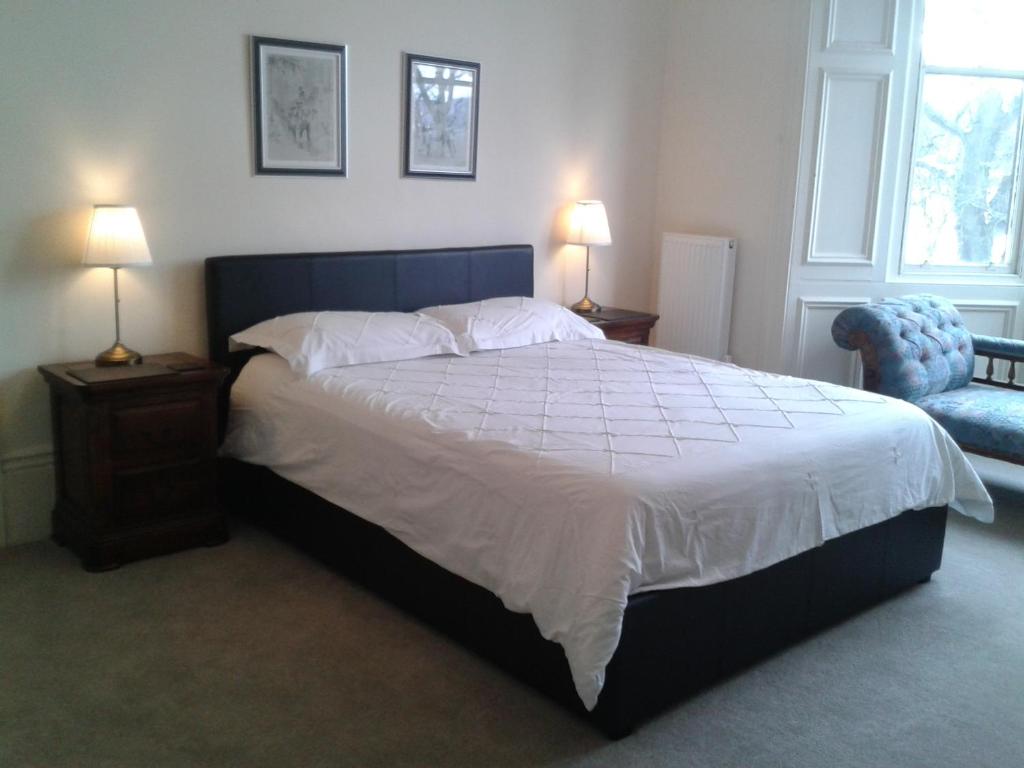 a bedroom with a large bed with two lamps and a chair at The Haven in Gateshead