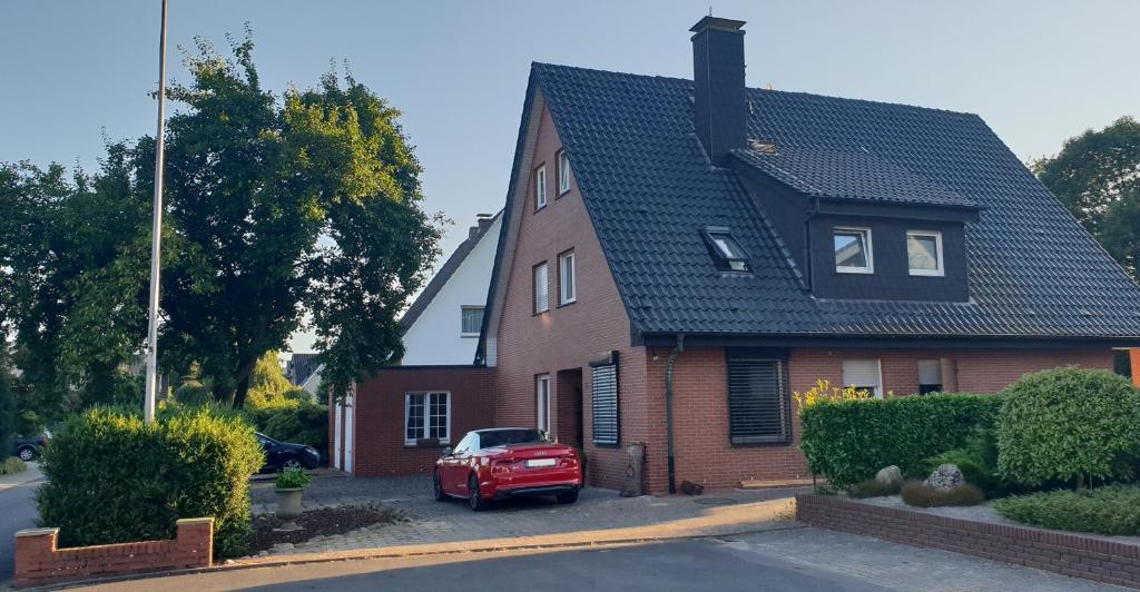 ein rotes Auto, das vor einem Haus parkt in der Unterkunft Pension Pommernweg Ibbenbüren in Ibbenbüren