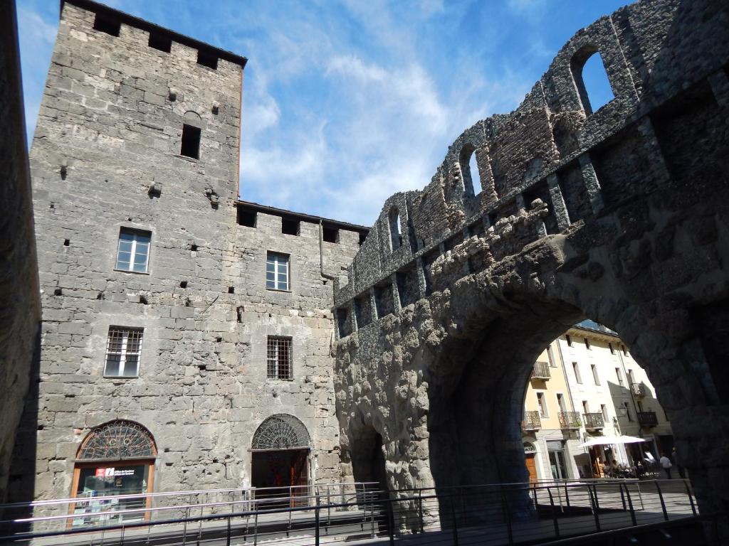 a large stone building with an arch in front of it at Appartamento da Paolo Love Aosta in Aosta