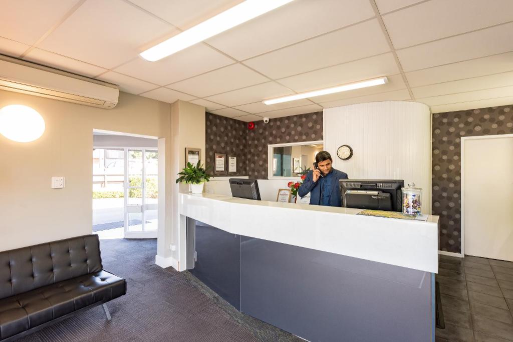 a man standing at a counter in a waiting room at Heartland Ambassador Hotel Hamilton in Hamilton