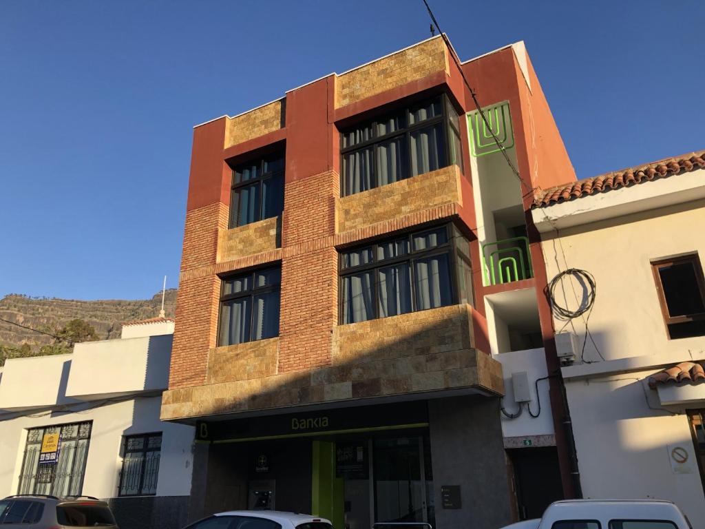 a brick building with cars parked in front of it at Apartamentos Acorán Mogán in Mogán