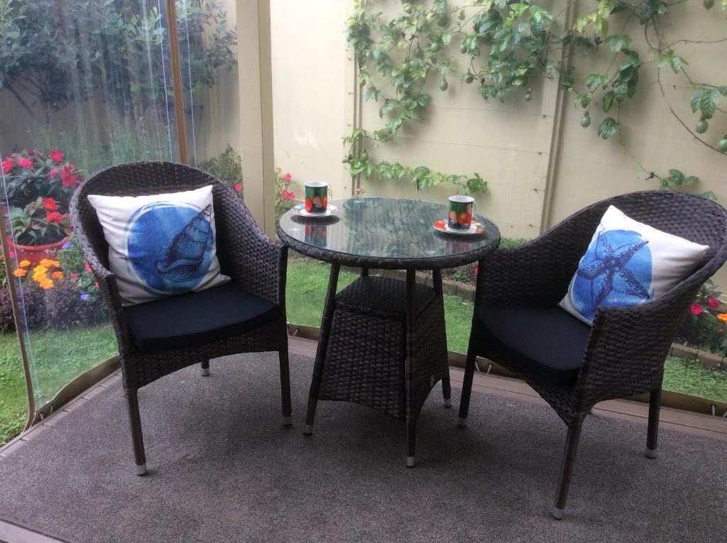 twee stoelen en een glazen tafel met twee bekers erop bij Albert Mews B and B in Whitianga