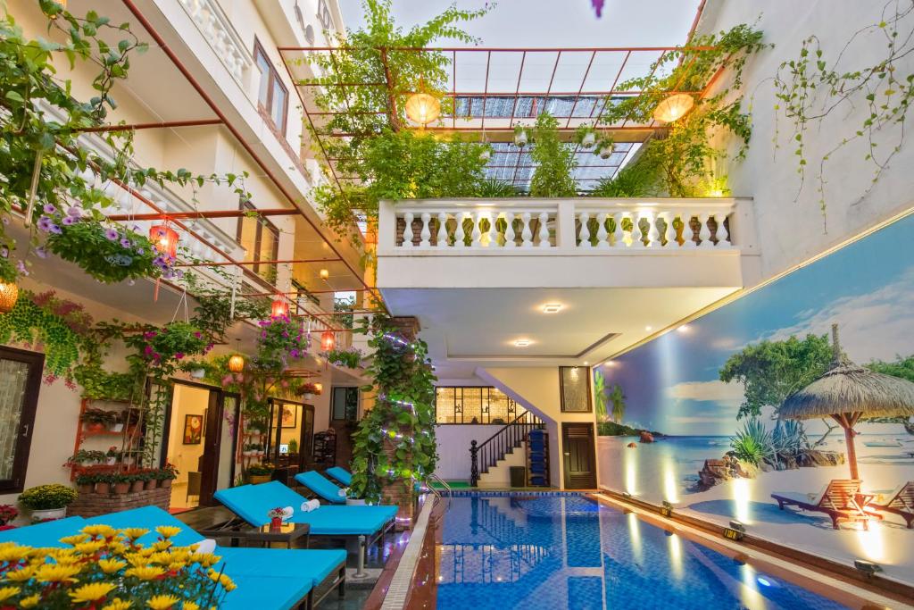 een hotelzwembad met blauwe tafels en planten bij Pham Gia Boutique Villa in Hội An