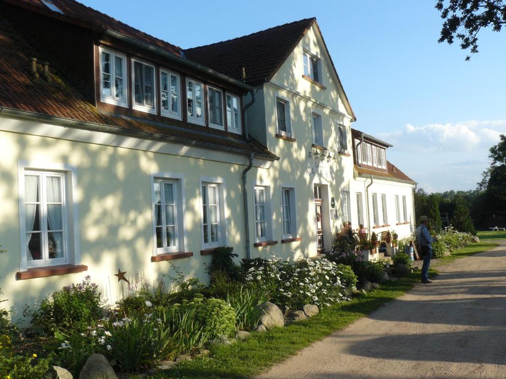 a man standing in front of a white house at Hotel Gutshaus Kajahn in Gustow