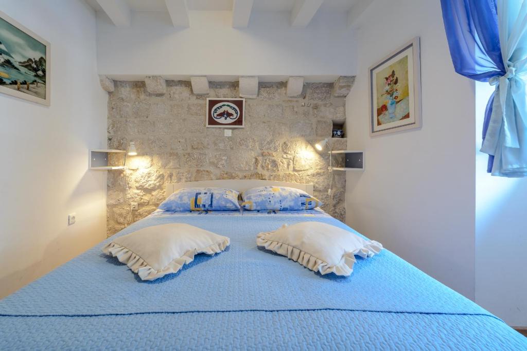 1 dormitorio con cama azul y almohadas en Studio Stradun, en Dubrovnik