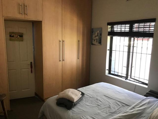 a bedroom with a bed and cabinets and a window at At 27 on Derby in Cape Town