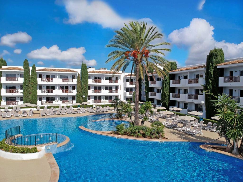 - une piscine avec des chaises longues et un palmier dans l'établissement Inturotel Azul Garden, à Cala d´Or