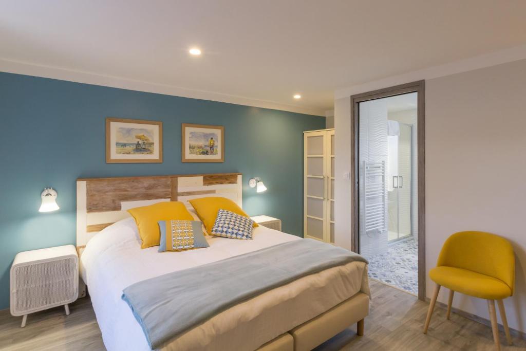 een slaapkamer met een groot bed en een gele stoel bij Chambre d'hôtes La Longère in Sotteville