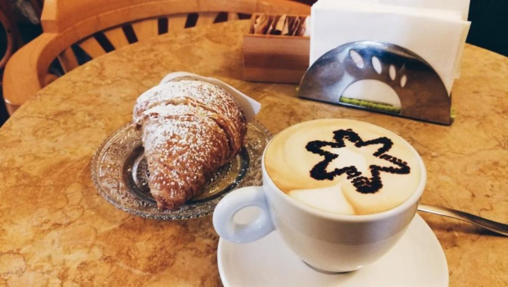 uma chávena de café e um bolo numa mesa em Affittacamere I Gatti delle 5 Terre em La Spezia