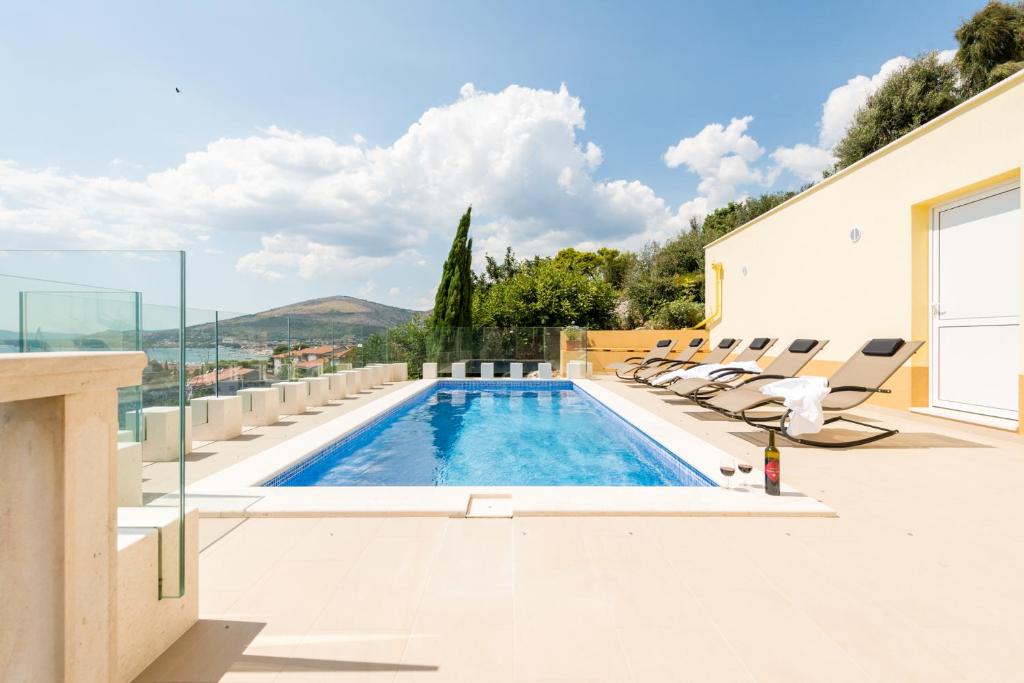 a swimming pool with lounge chairs on a house at Villa Boris in Trogir